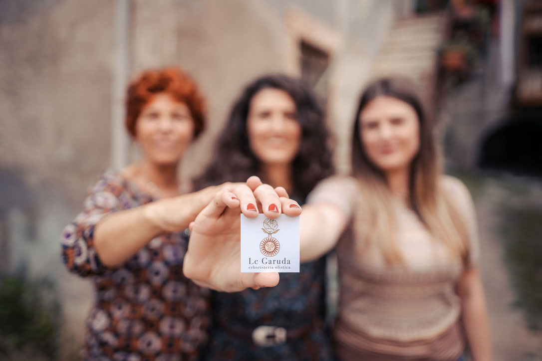Le fondatrici del Le Garuda che insieme mostrano il logo dell'erboristeria