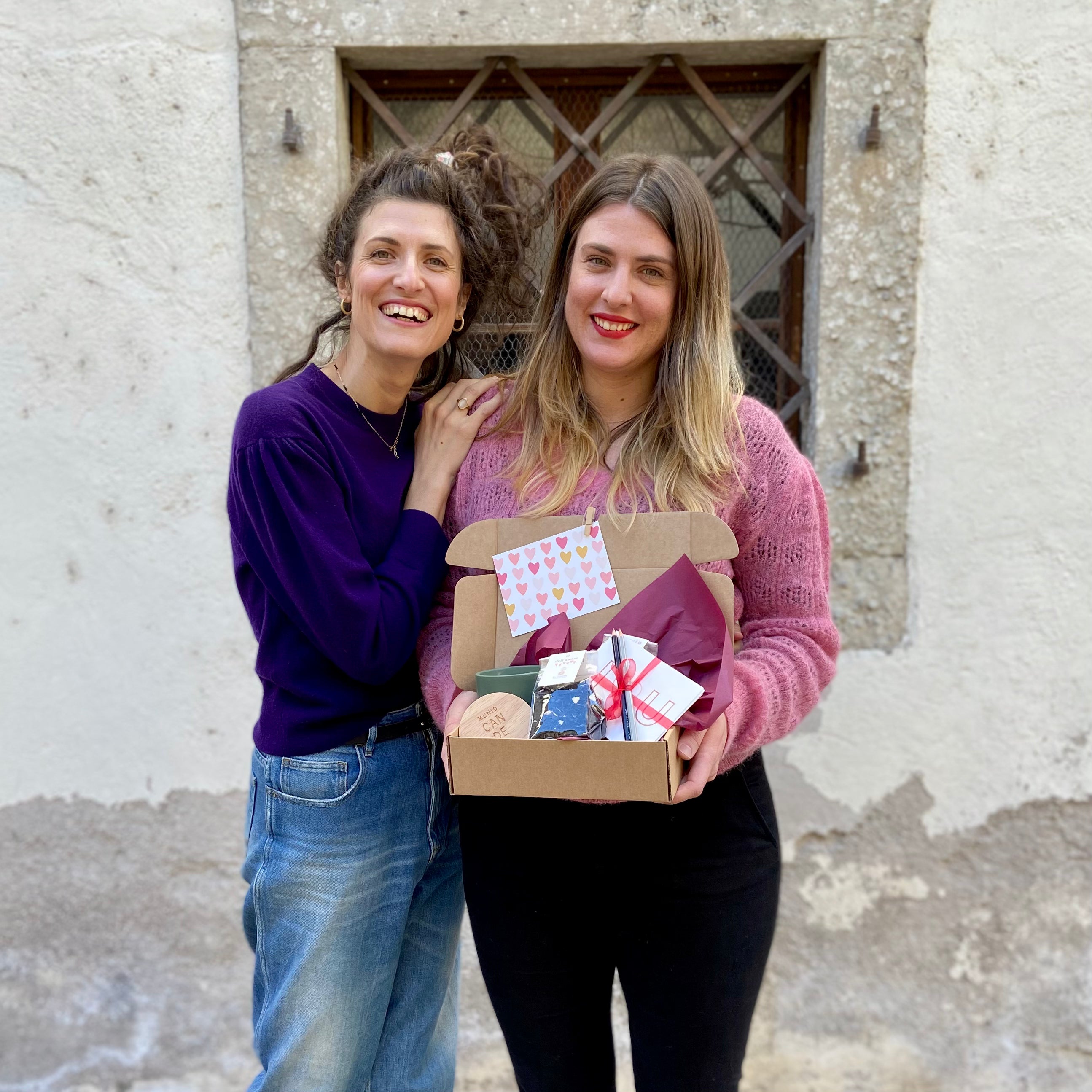 Giulia e Claudia sorridenti, tengono in mano una box piena di prodotti